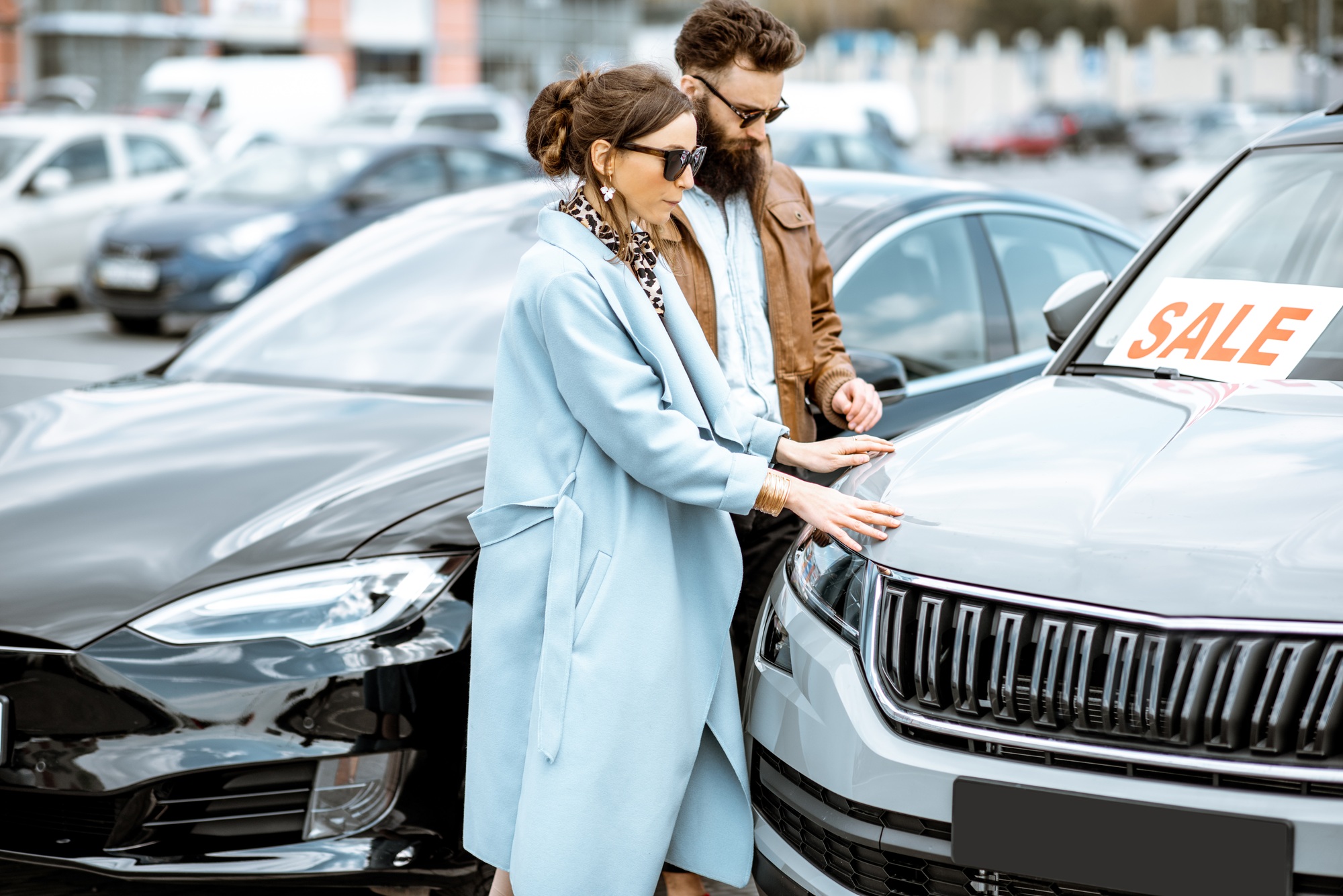 Man and woman choosing car to buy outdoors