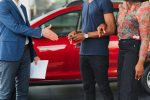 salesman showing new car to african couple in showroom